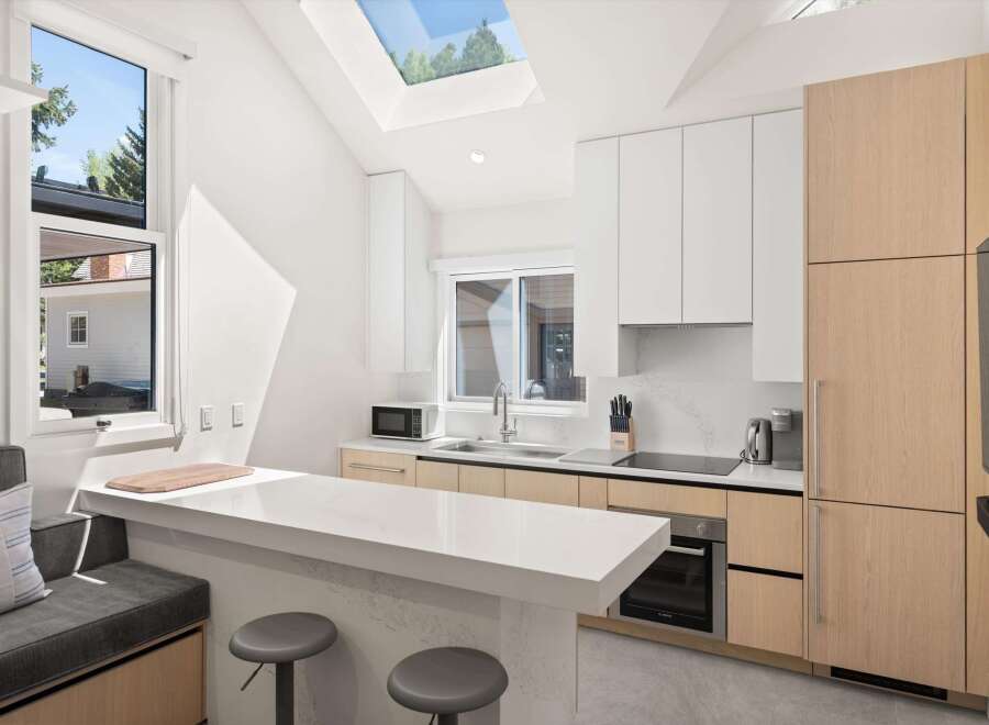 This stunning kitchen boasts a modern design with sleek white countertops and light wood cabinets.