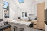 This stunning kitchen boasts a modern design with sleek white countertops and light wood cabinets.