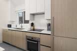 Modern kitchen with light wood cabinets, stainless steel appliances, and quartz countertops.