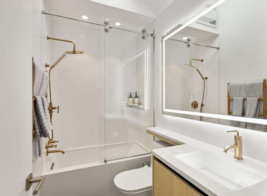 This stunning bathroom boasts a modern design with sleek gold fixtures and a frameless glass shower enclosure.