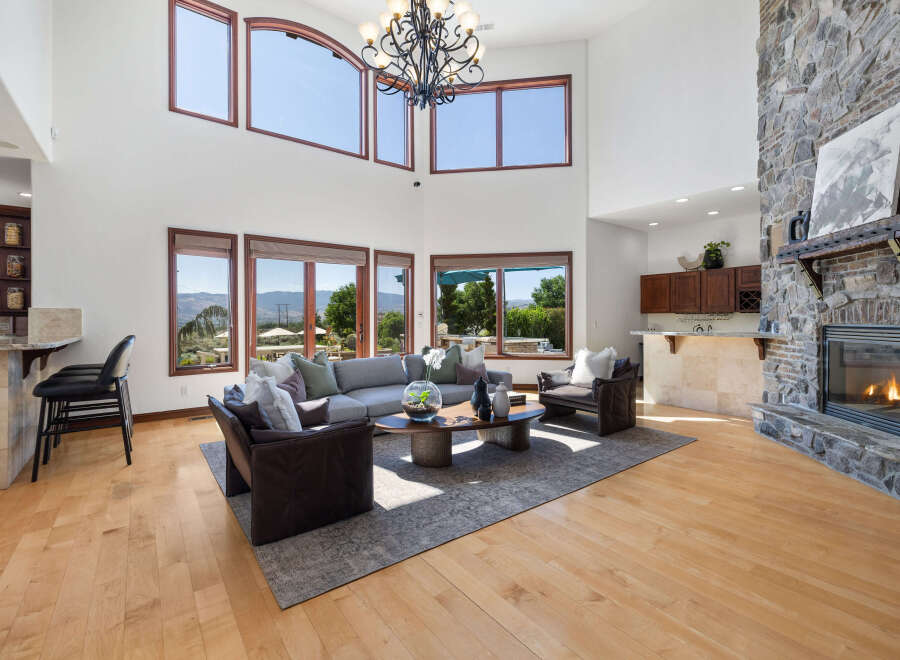 This stunning home boasts a spacious living area with hardwood floors, floor-to-ceiling windows offering breathtaking views, and a cozy stone fireplace.