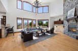 This stunning home boasts a spacious living area with hardwood floors, floor-to-ceiling windows offering breathtaking views, and a cozy stone fireplace.