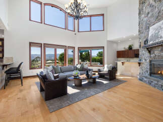 This stunning home boasts a spacious living area with hardwood floors, floor-to-ceiling windows offering breathtaking views, and a cozy stone fireplace.