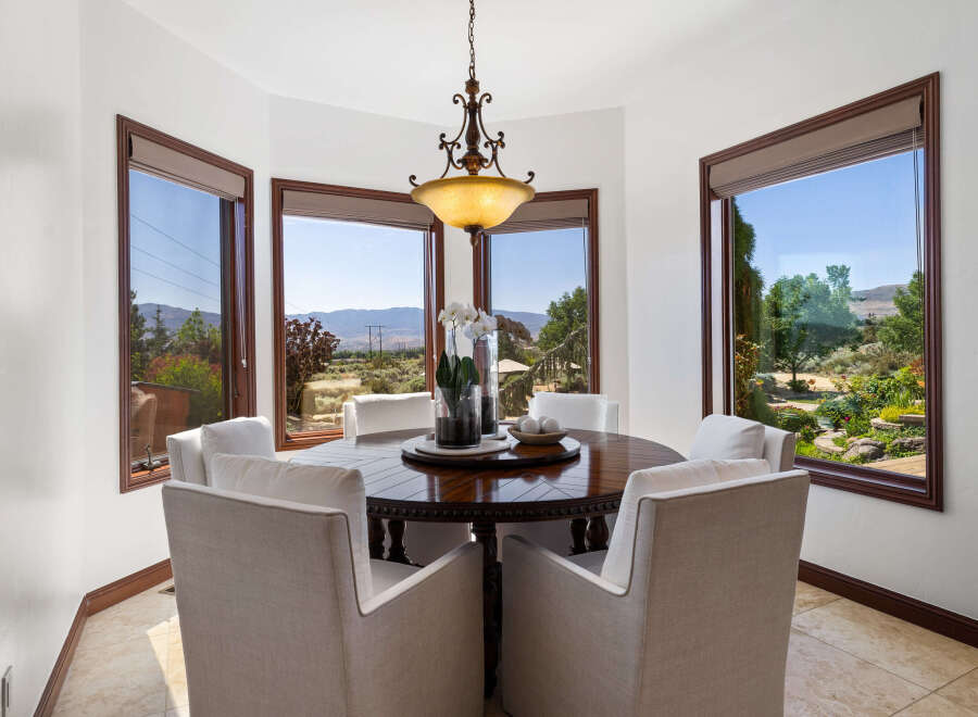 This stunning dining room boasts a breathtaking view, thanks to its large windows showcasing rolling hills and lush greenery.