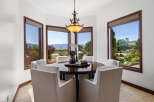 This stunning dining room boasts a breathtaking view, thanks to its large windows showcasing rolling hills and lush greenery.