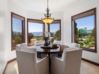This stunning dining room boasts a breathtaking view, thanks to its large windows showcasing rolling hills and lush greenery.