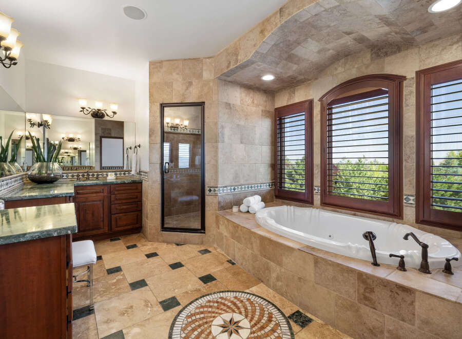 This luxurious master bathroom boasts a spacious layout with dual vanities, a large soaking tub, and a separate shower.