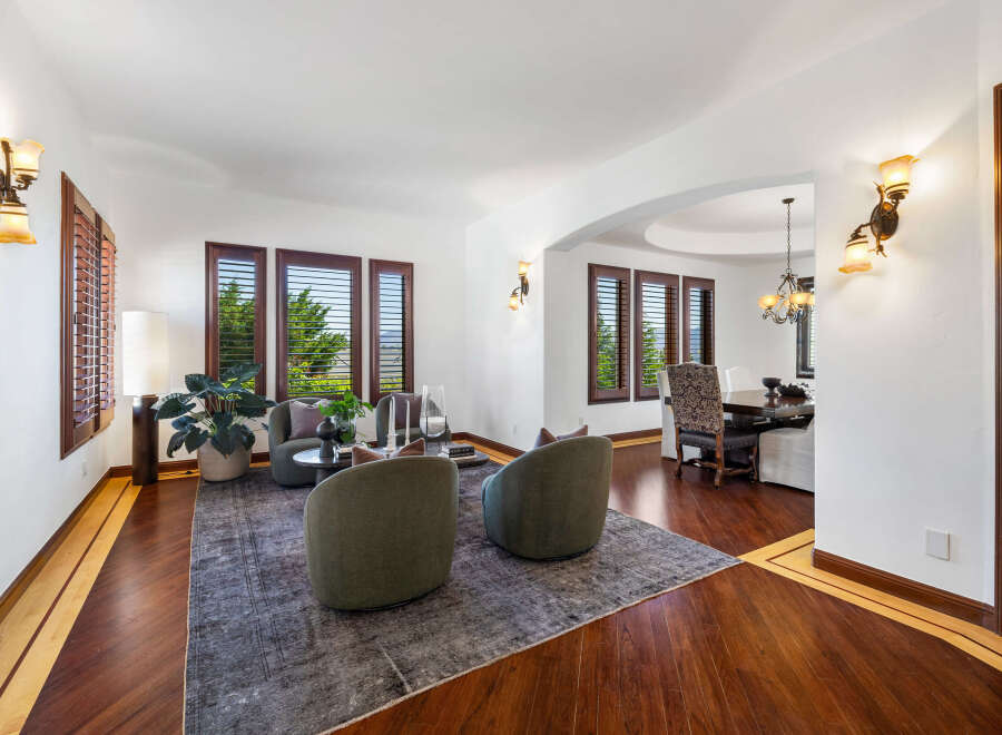This stunning home boasts a spacious living area with hardwood floors, plantation shutters, and a cozy seating arrangement.