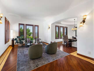 This stunning home boasts a spacious living area with hardwood floors, plantation shutters, and a cozy seating arrangement.