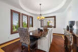 This elegant dining room boasts a stunning hardwood floor, complemented by rich wood furniture and large windows with plantation shutters.