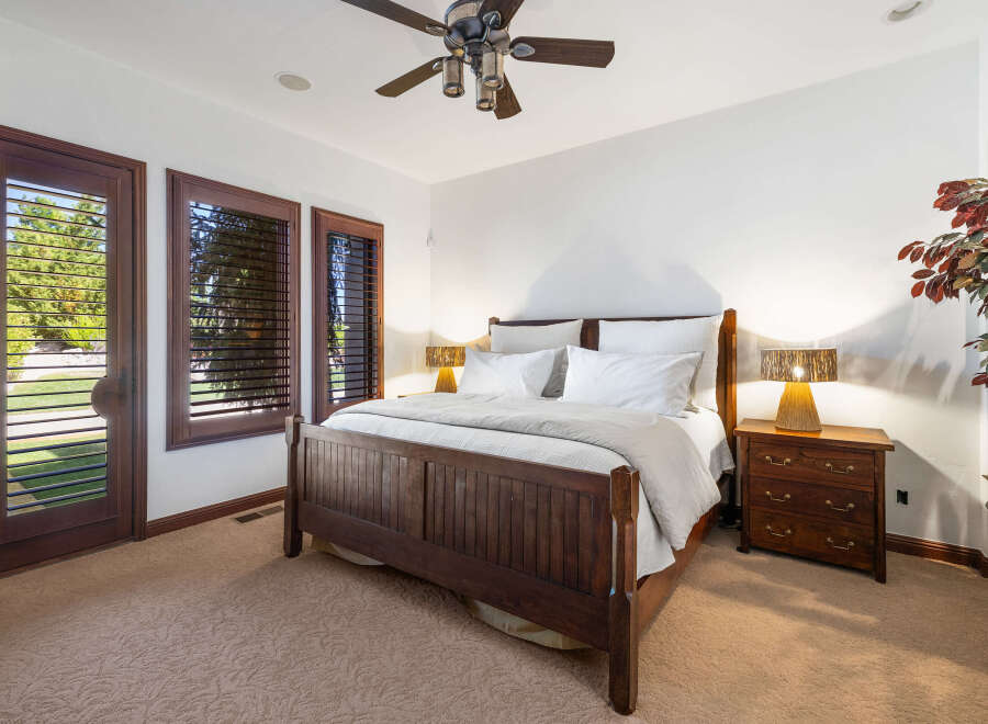 This luxurious bedroom boasts a king-size bed with a wooden frame, complemented by plush bedding and nightstands with lamps.