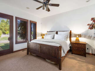 This luxurious bedroom boasts a king-size bed with a wooden frame, complemented by plush bedding and nightstands with lamps.