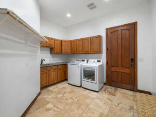 This stunning laundry room boasts ample storage with custom wood cabinets and a convenient built-in hanging rod.