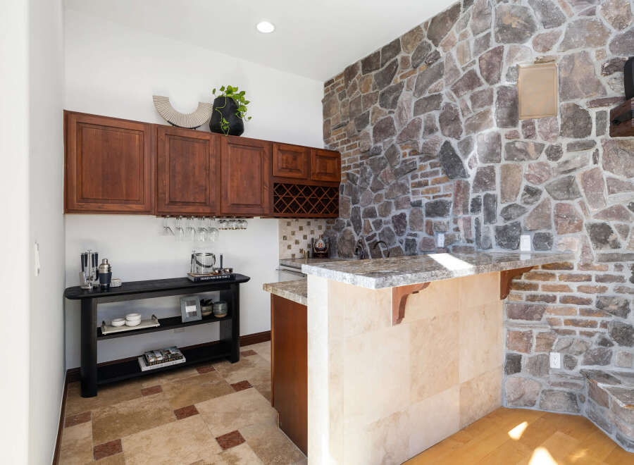 This stunning home boasts a built-in bar with granite countertops and custom cabinetry, perfect for entertaining guests.