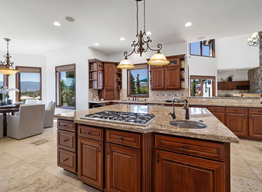 This stunning kitchen boasts a large island with granite countertops, a gas cooktop, and ample cabinetry.