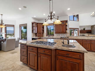 This stunning kitchen boasts a large island with granite countertops, a gas cooktop, and ample cabinetry.