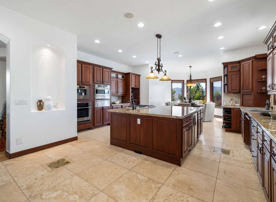 This stunning kitchen boasts beautiful dark wood cabinetry, granite countertops, and high-end stainless steel appliances.