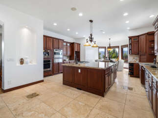 This stunning kitchen boasts beautiful dark wood cabinetry, granite countertops, and high-end stainless steel appliances.