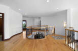 This stunning property boasts a grand curved staircase with intricate wrought iron railings and rich hardwood floors.