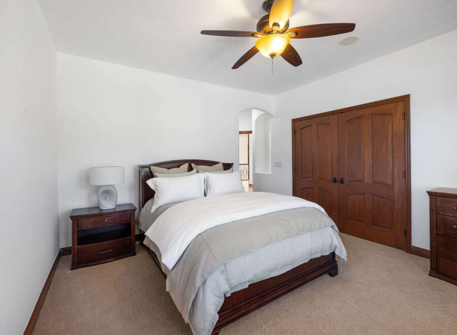 This bedroom boasts a cozy and elegant atmosphere, featuring a plush bed with a light grey duvet and crisp white sheets.