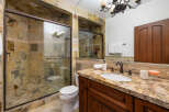 This luxurious bathroom boasts a spacious shower with glass enclosure and multi-toned stone tile.