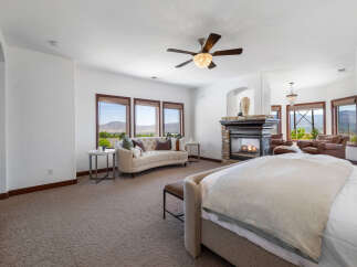Luxurious master bedroom with stunning mountain views and a cozy fireplace.
