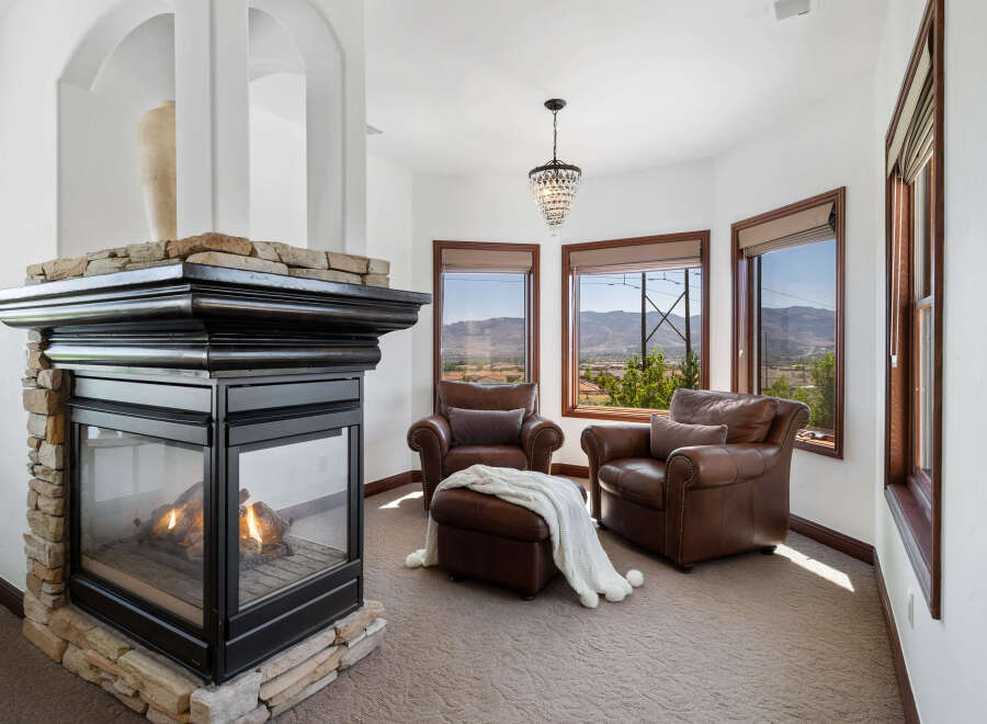 Cozy up by the fireplace in this stunning room, featuring a stone fireplace and large windows offering breathtaking views.