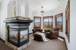 Cozy up by the fireplace in this stunning room, featuring a stone fireplace and large windows offering breathtaking views.
