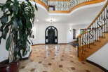 This stunning home boasts a grand foyer with a beautiful travertine tile floor, a sweeping staircase with wrought iron railings, and a dramatic arched entry door.