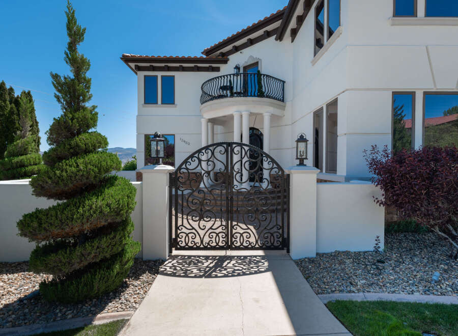 This stunning property boasts a grand entrance with an ornate wrought iron gate, leading to a luxurious Mediterranean-style home.