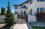 This stunning property boasts a grand entrance with an ornate wrought iron gate, leading to a luxurious Mediterranean-style home.