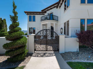 This stunning property boasts a grand entrance with an ornate wrought iron gate, leading to a luxurious Mediterranean-style home.