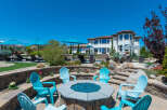 This stunning property boasts a luxurious outdoor space, complete with a fire pit, comfortable seating, and multiple umbrellas for shade.