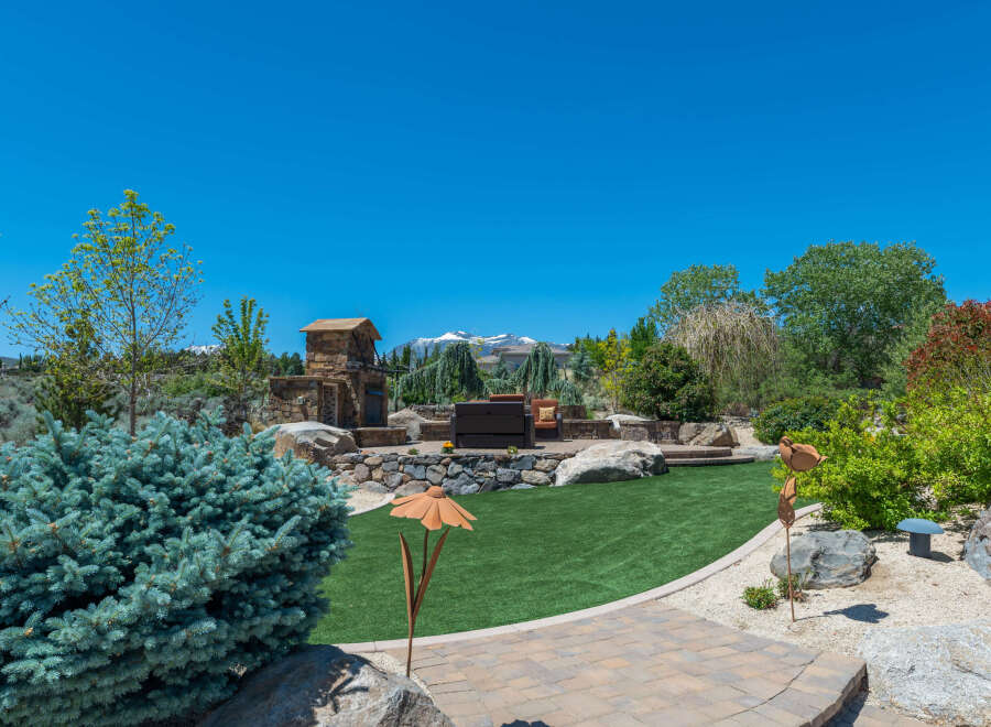 This stunning property boasts a beautifully landscaped backyard, complete with a stone fireplace and seating area, perfect for outdoor entertaining.