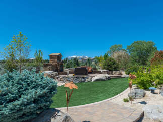 This stunning property boasts a beautifully landscaped backyard, complete with a stone fireplace and seating area, perfect for outdoor entertaining.