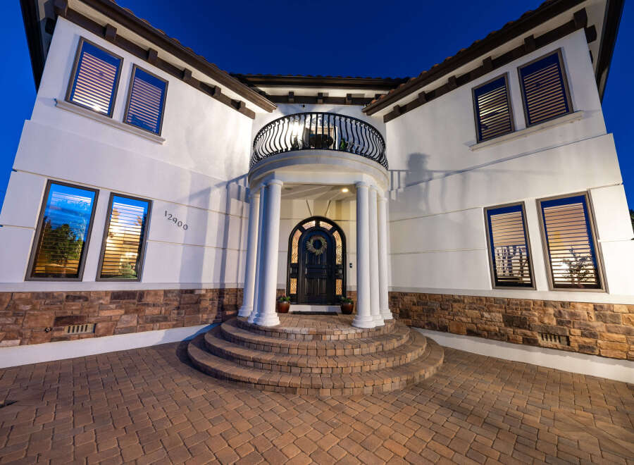 This stunning Mediterranean-style home boasts a grand entrance with a curved staircase, elegant columns, and a charming balcony.