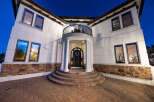 This stunning Mediterranean-style home boasts a grand entrance with a curved staircase, elegant columns, and a charming balcony.