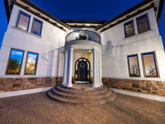 This stunning Mediterranean-style home boasts a grand entrance with a curved staircase, elegant columns, and a charming balcony.