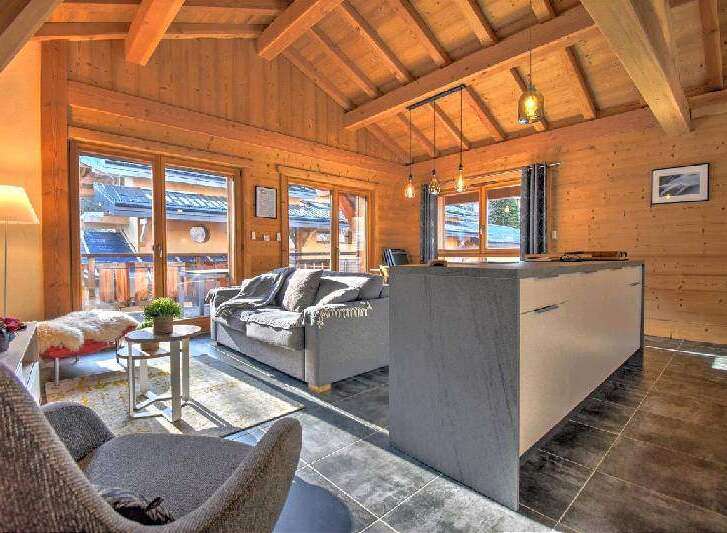 This stunning chalet boasts a spacious open-plan living area with floor-to-ceiling windows offering breathtaking mountain views.