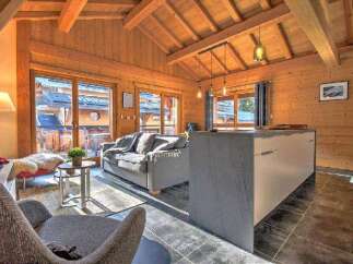 This stunning chalet boasts a spacious open-plan living area with floor-to-ceiling windows offering breathtaking mountain views.