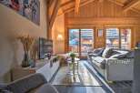 This stunning chalet boasts a spacious living area with floor-to-ceiling windows offering breathtaking mountain views.