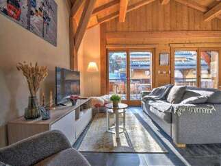 This stunning chalet boasts a spacious living area with floor-to-ceiling windows offering breathtaking mountain views.