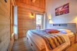 Cozy chalet bedroom with wooden walls and a comfy bed.