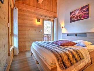 Cozy chalet bedroom with wooden walls and a comfy bed.