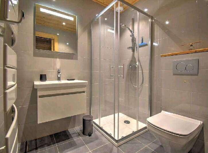 Modern bathroom with a walk-in shower, sleek vanity, and a wall-mounted toilet.