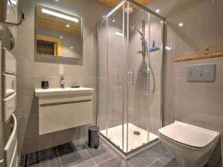 Modern bathroom with a walk-in shower, sleek vanity, and a wall-mounted toilet.