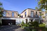Stunning modern home nestled in a lush landscape, featuring a spacious garage and a sleek design.