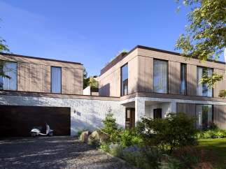 Stunning modern home nestled in a lush landscape, featuring a spacious garage and a sleek design.