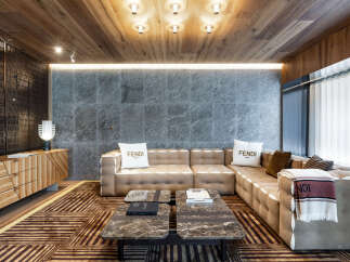 Luxury living room with Fendi decor, featuring a large sectional sofa, marble coffee tables, and a wood-paneled ceiling.