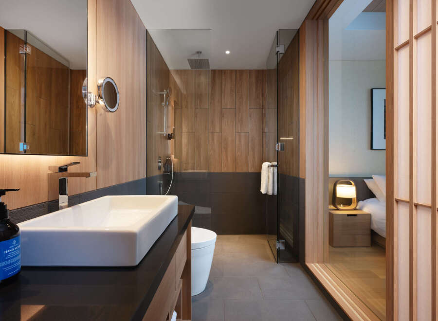 This modern hotel bathroom boasts a sleek, minimalist design with a walk-in shower and a spacious vanity.